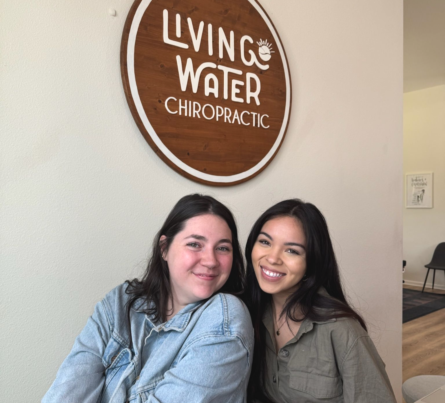 Two women smiling behind the desk at Living Water Chiropractic