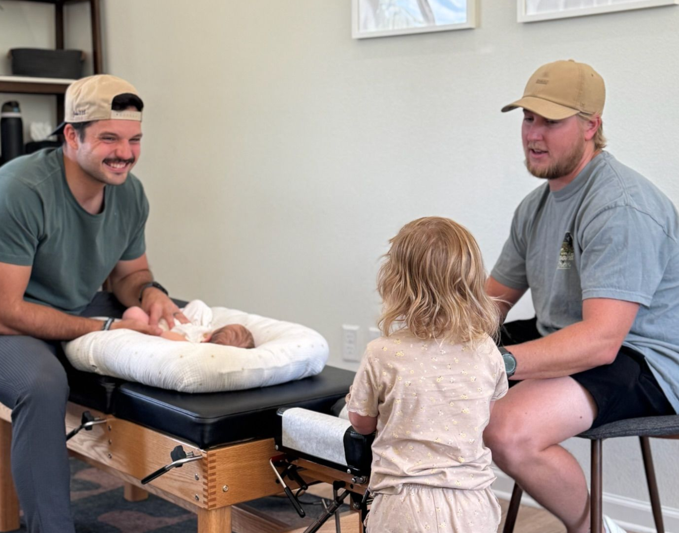 Dr. Rudy adjusting an infant while the sister and father watch, smiling.