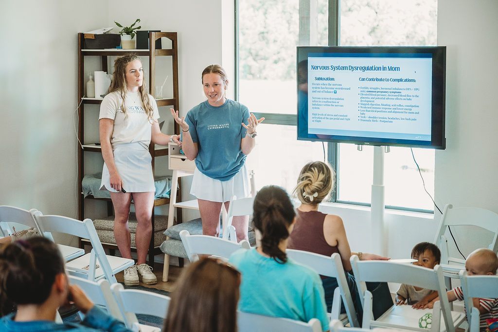 Presenter and audience in a bright classroom watching a slide on a large TV screen