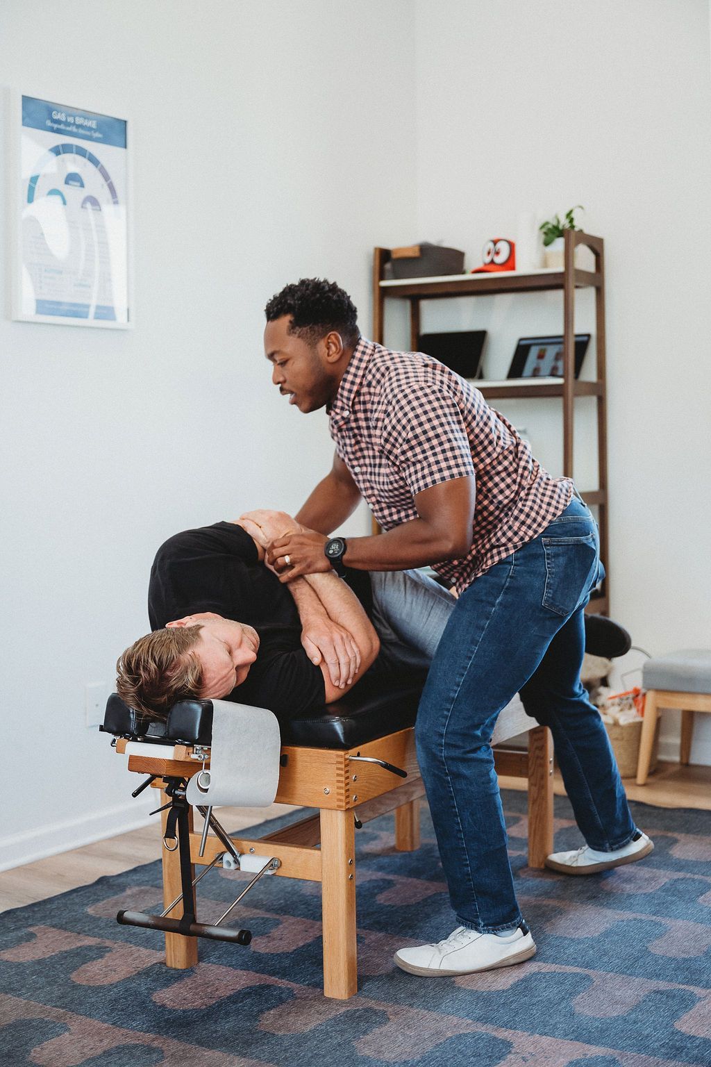 Chiropractor adjusts a client on a treatment table in a clinic room.