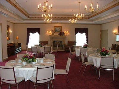 Elegant banquet hall with round tables, white tablecloths, chandeliers, and a fireplace at the far end