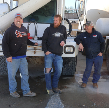 Three men are standing in front of a concrete mixer truck