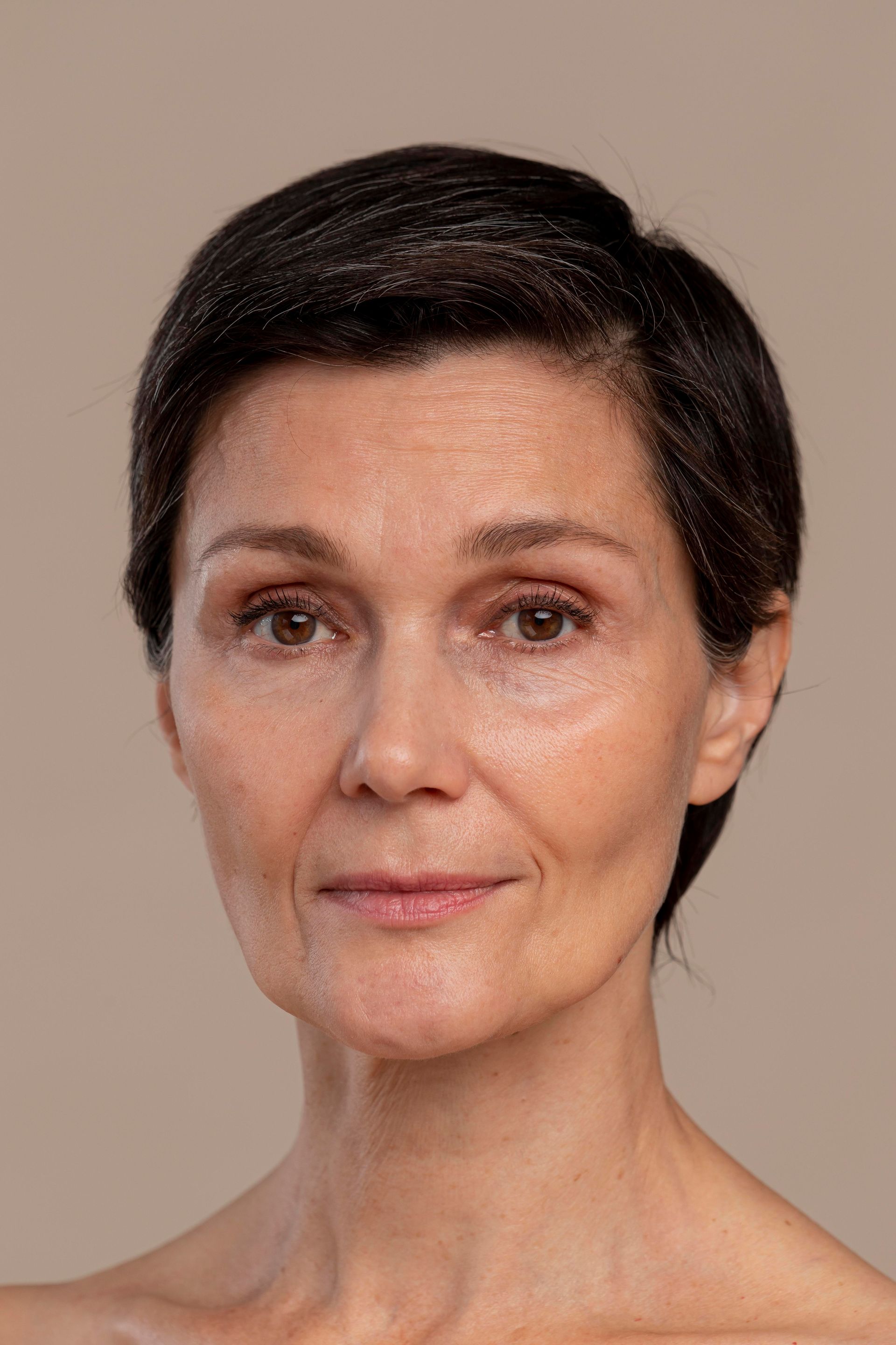 Portrait of a person with short dark hair against a plain beige background