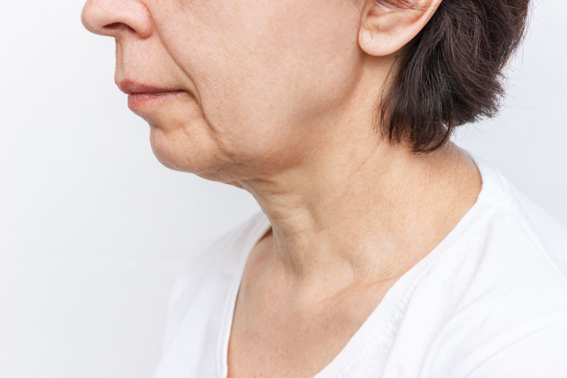 Side profile of a person touching the front of their neck against a plain white background