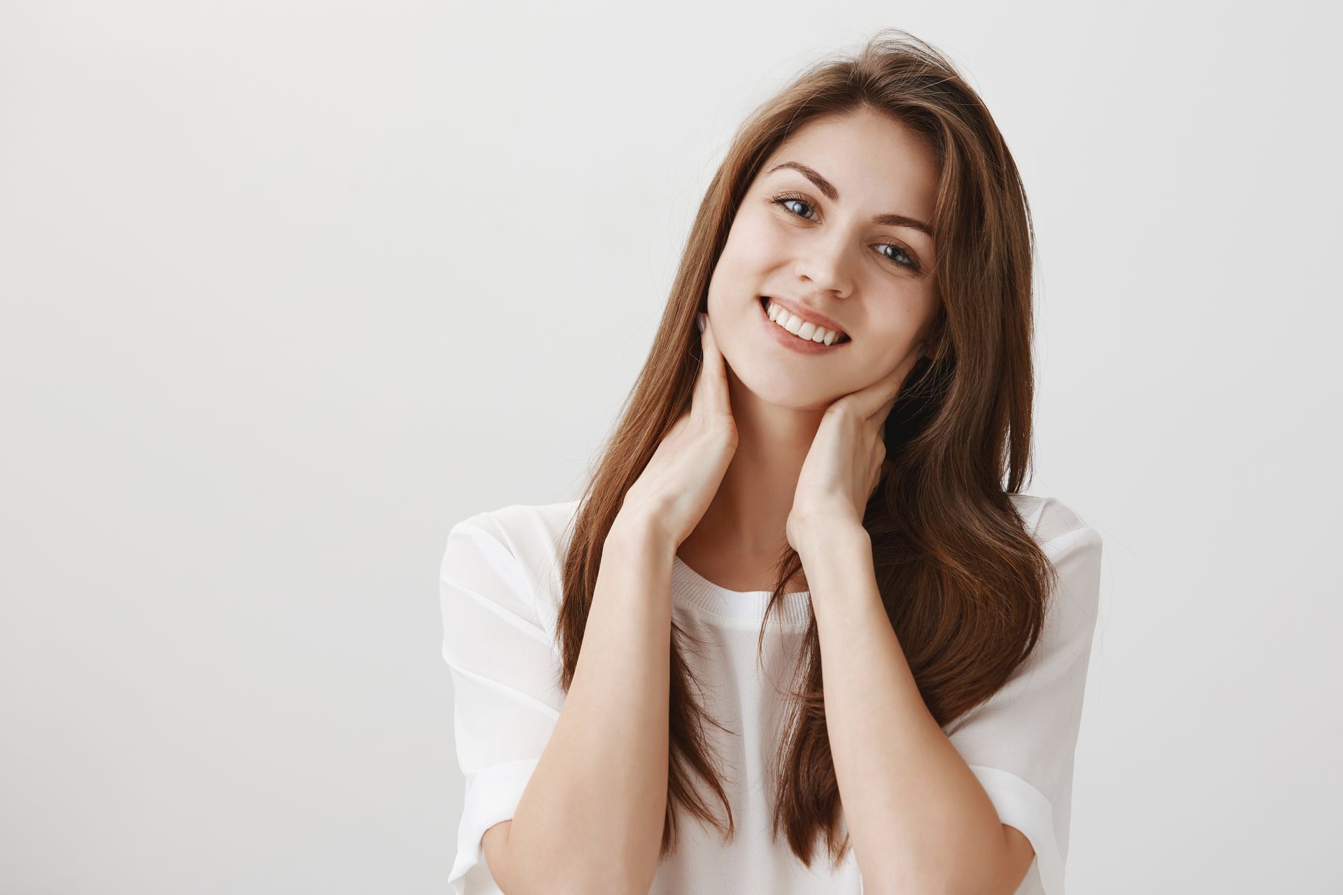 a woman smiling and touching her neck