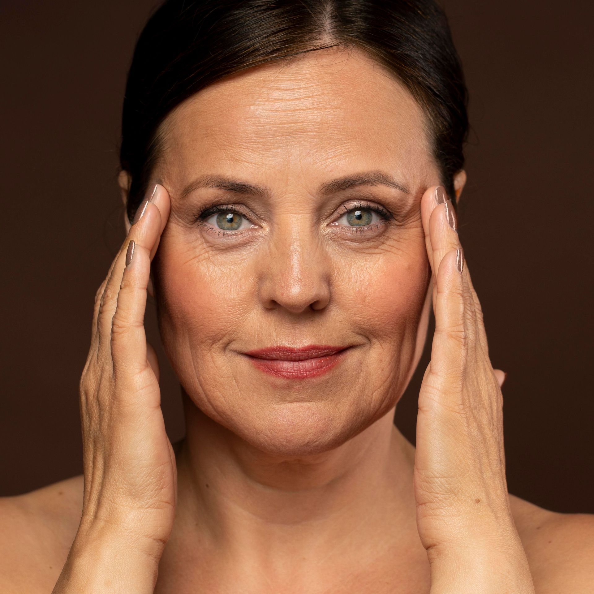 Portrait of a woman touching her temples against a dark background