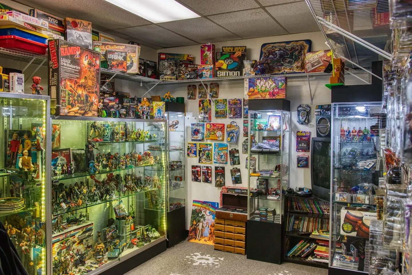 A small toy store with shelves and glass display cases filled with various action figures and boxed collectibles.