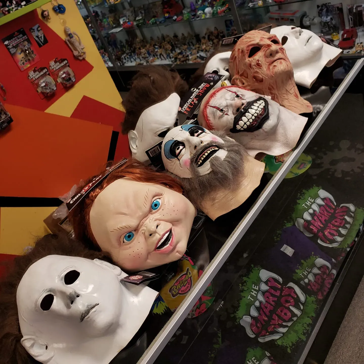 A store shelf displays an assortment of horror character masks, including Chucky, Michael Myers, captain spaulding, twisty the clown and Freddy Krueger.