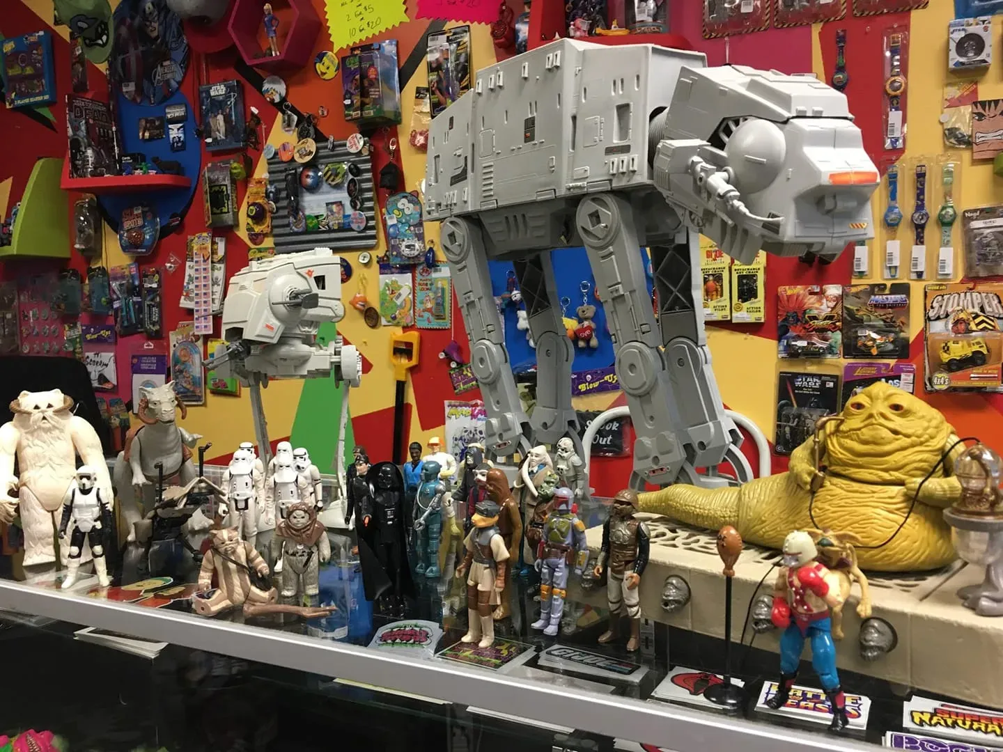 A display of Star Wars toys, including a large AT-AT walker, a Jabba the Hutt figure, and various action figures.