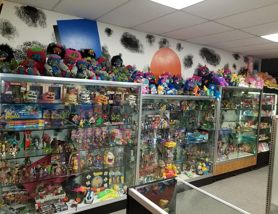Glass display cases filled with toys and collectibles inside a store, with many stuffed dolls lined up along the top.
