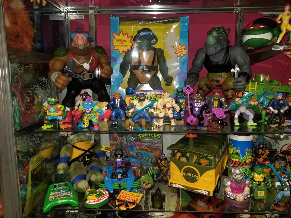 A shelf display of Teenage Mutant Ninja Turtles action figures, vehicles, and collectibles.
