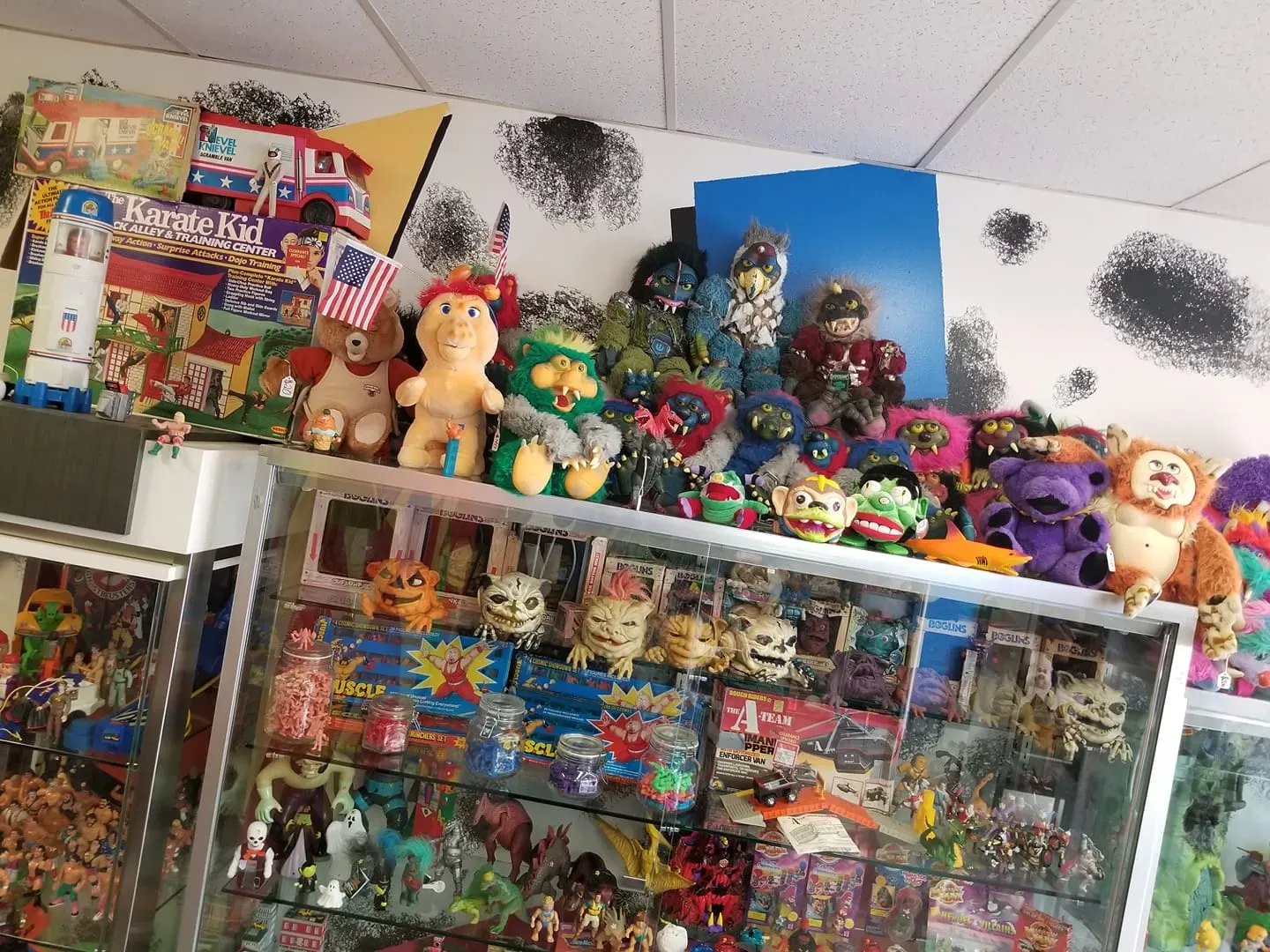 A store display shelf overflowing with vintage plush toys and assorted action figures.