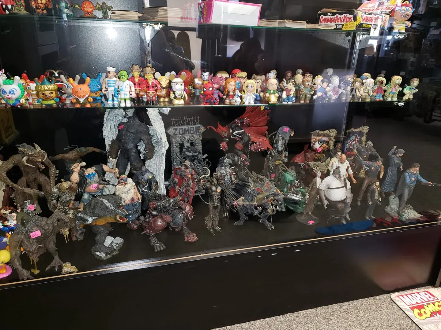 A display shelf filled with numerous collectible action figures, figurines, and toys arranged on two levels.
