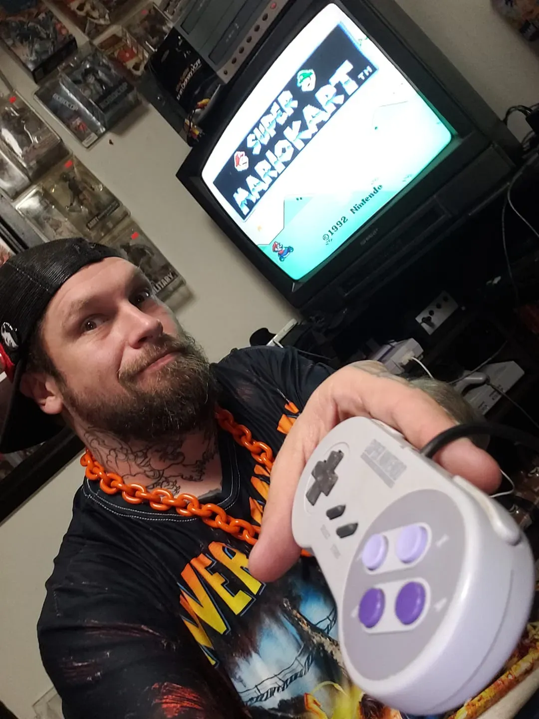 Brandon holds a SNES controller in front of a TV showing Super Mario Kart.