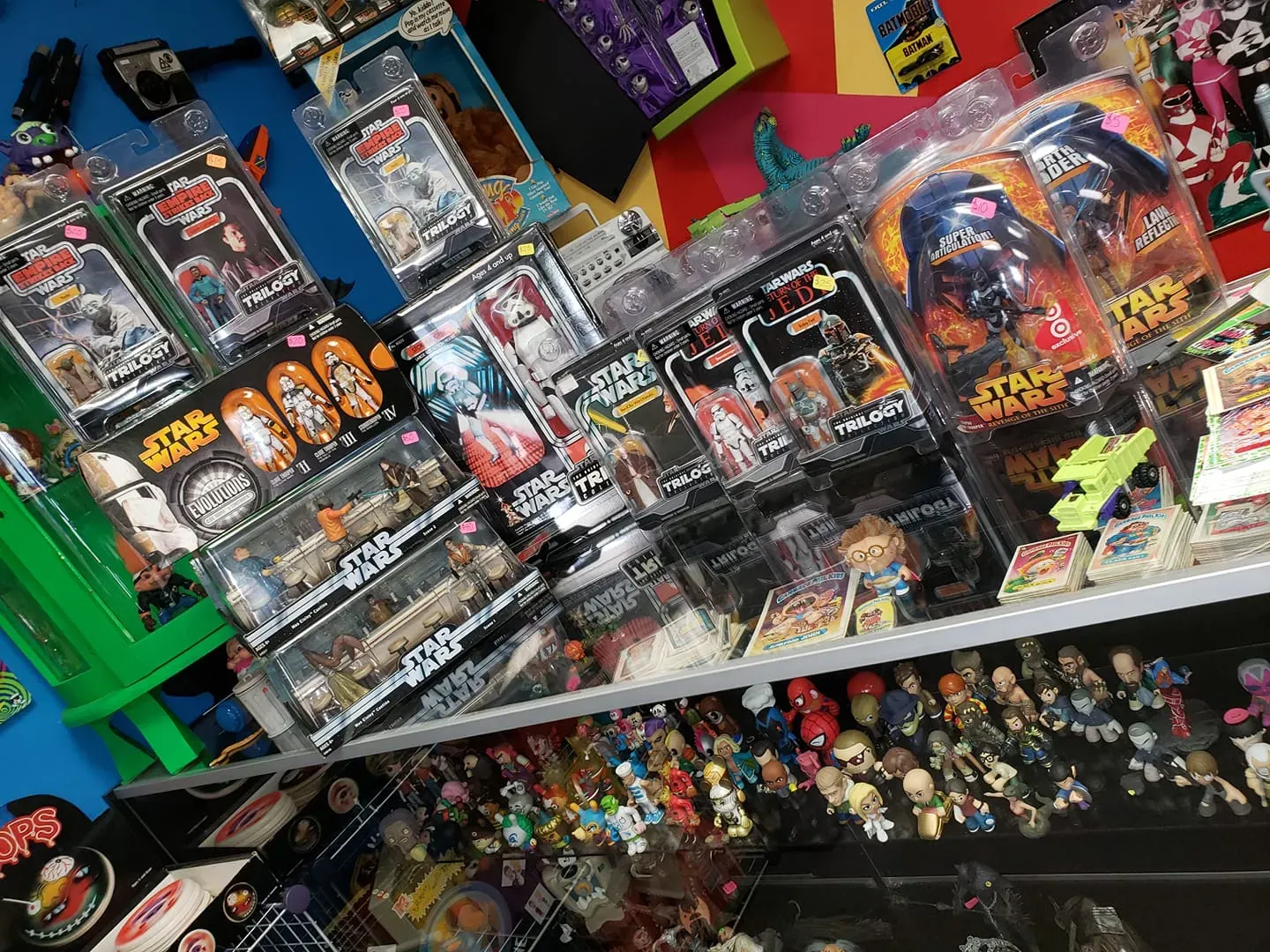 A retail store display featuring numerous Star Wars action figures in their original packaging, organized on shelves.