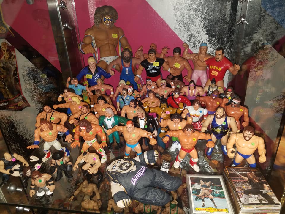 A display case filled with numerous vintage wrestling action figures arranged on multiple levels.
