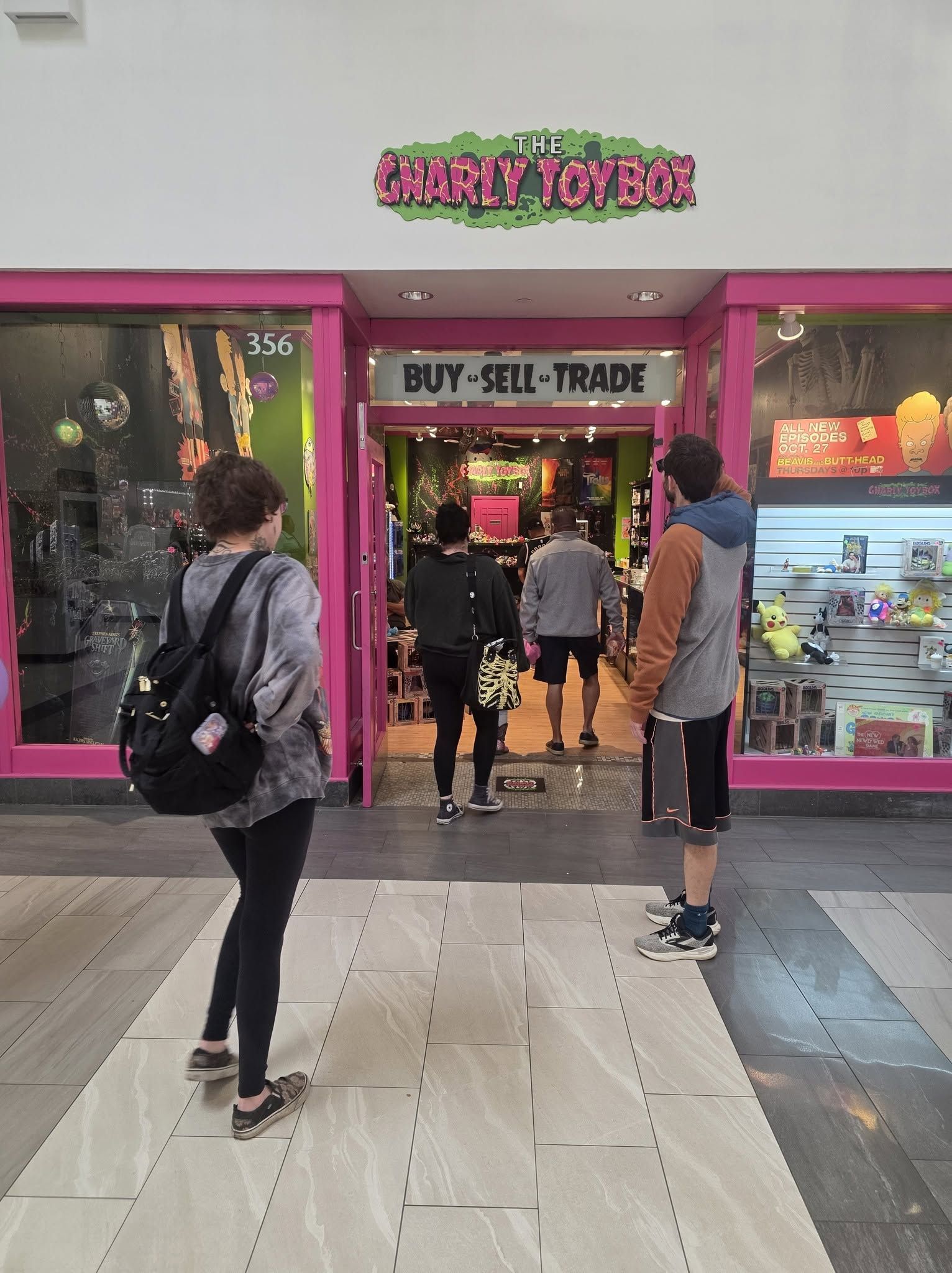 People entering a pink storefront with a bright sign and open doorway in a shopping center. People entering a pink storefront with a bright sign and open doorway in a shopping center.