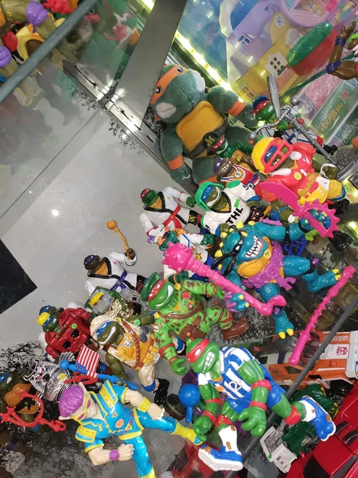A collection of Teenage Mutant Ninja Turtles action figures and toys arranged on a shelf.