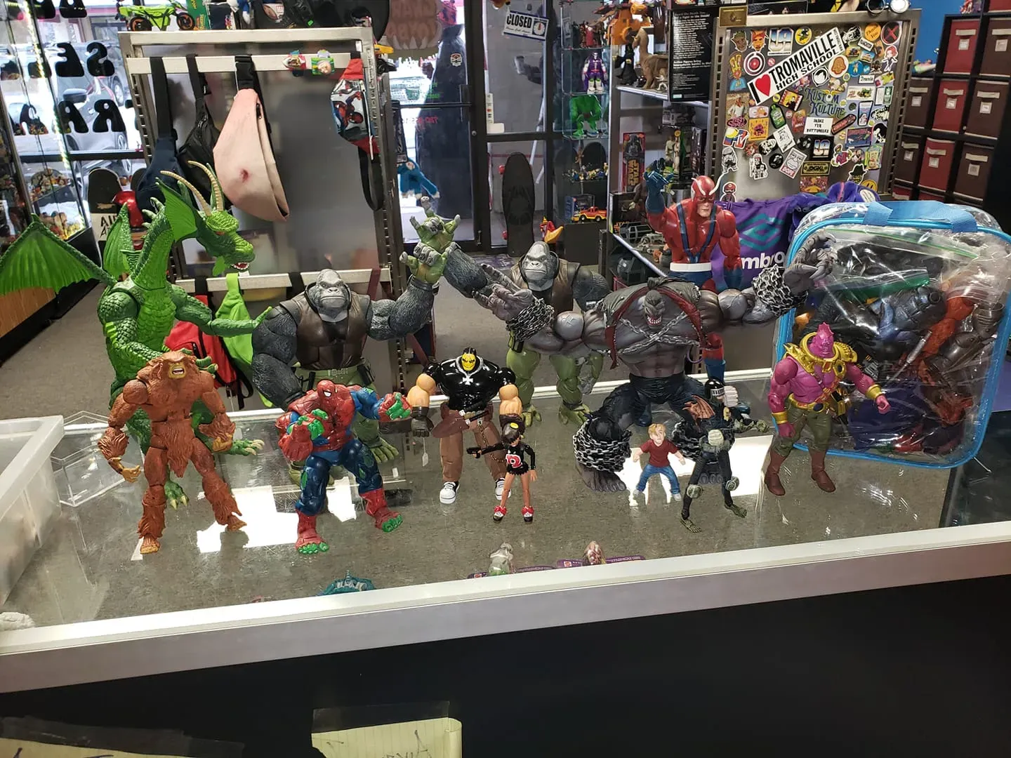 A display case at a store filled with various Marvel action figures, including a large green dragon and multiple heroes.