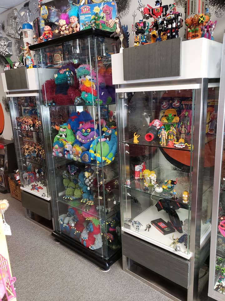 Glass display cases packed with colorful plush toys and action figures in a retail shop.