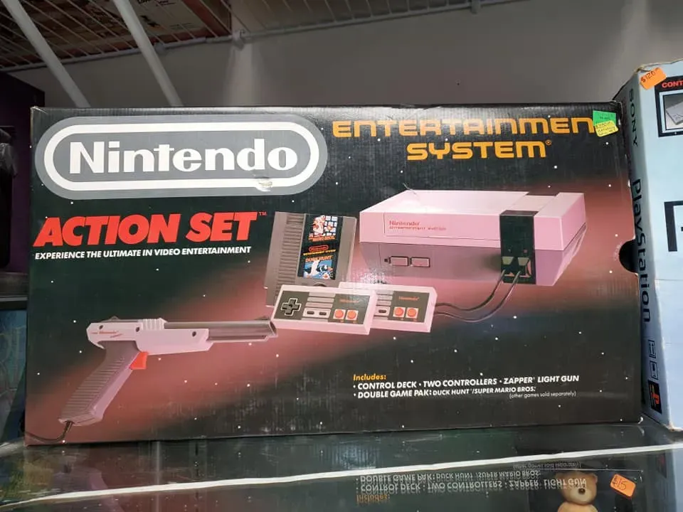 A Nintendo Entertainment System Action Set box featuring the console, two controllers, and a light gun on a dark background.