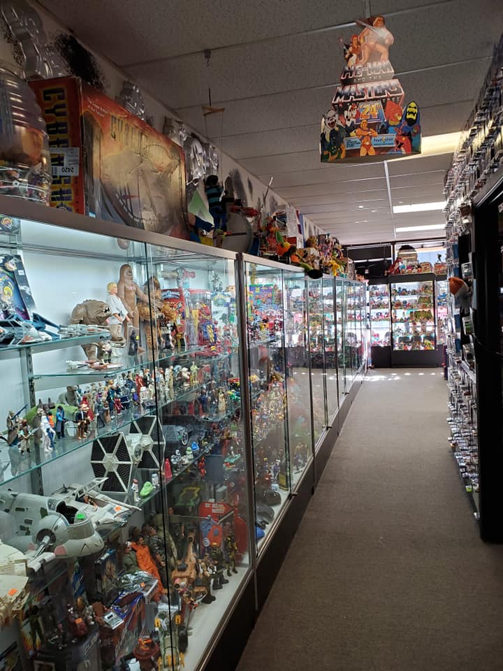 Long rows of glass display cases filled with vintage action figures and toy collectibles inside a store.