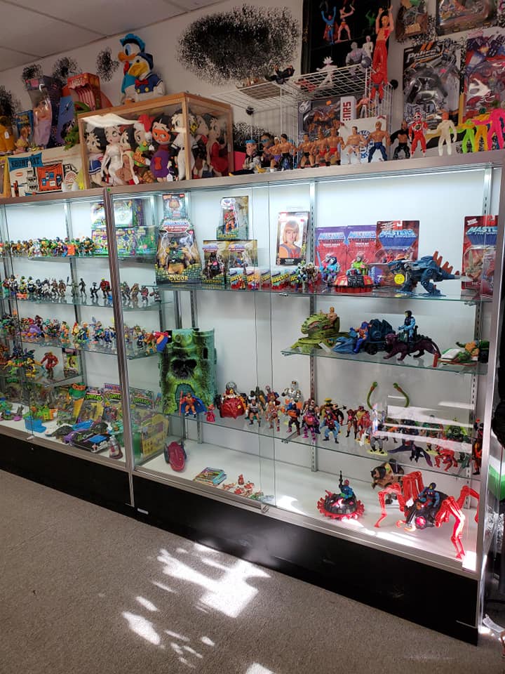 Display cases filled with vintage action figures and toys, featuring various characters on multiple shelves.