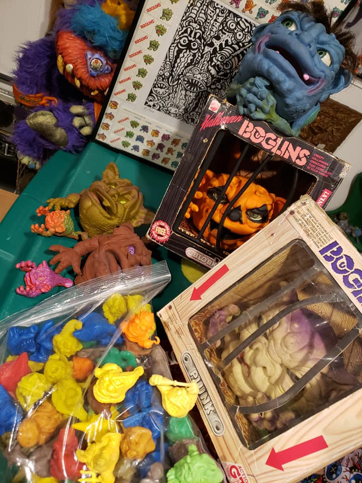 A collection of colorful Boglins monster toys, including some in boxes, loose figures, and a bag of miniature figurines. Beastuer, Hairy Boglin, boxed blobkin boglin and boglin stamp art.