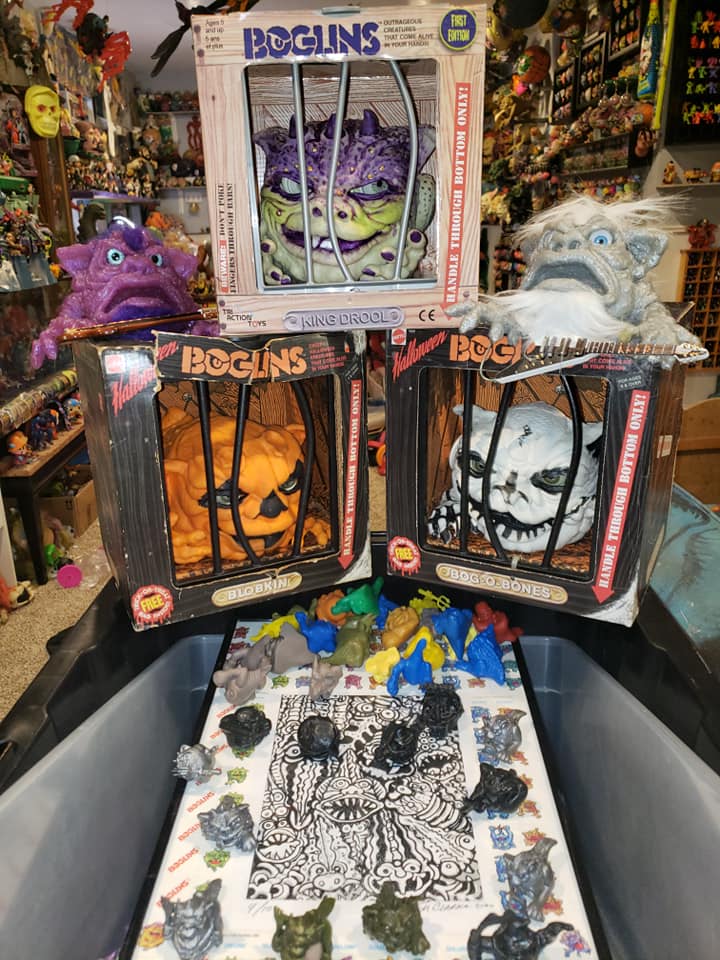 Collection of Boglins toys, including three in barred cages, one loose plush, and several miniature figures in a bin.