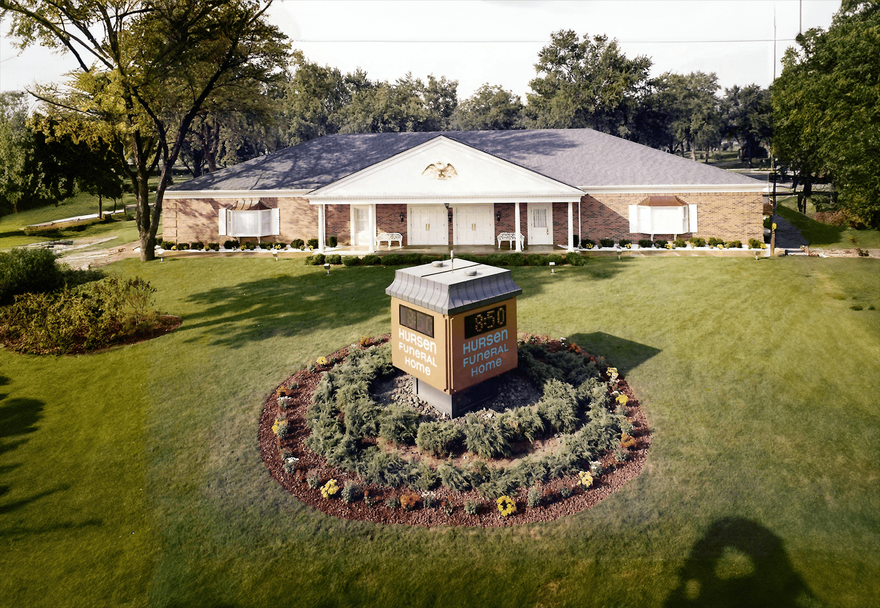 A suburban-style building with a lawn featuring a circular garden and a prominent monument sign.