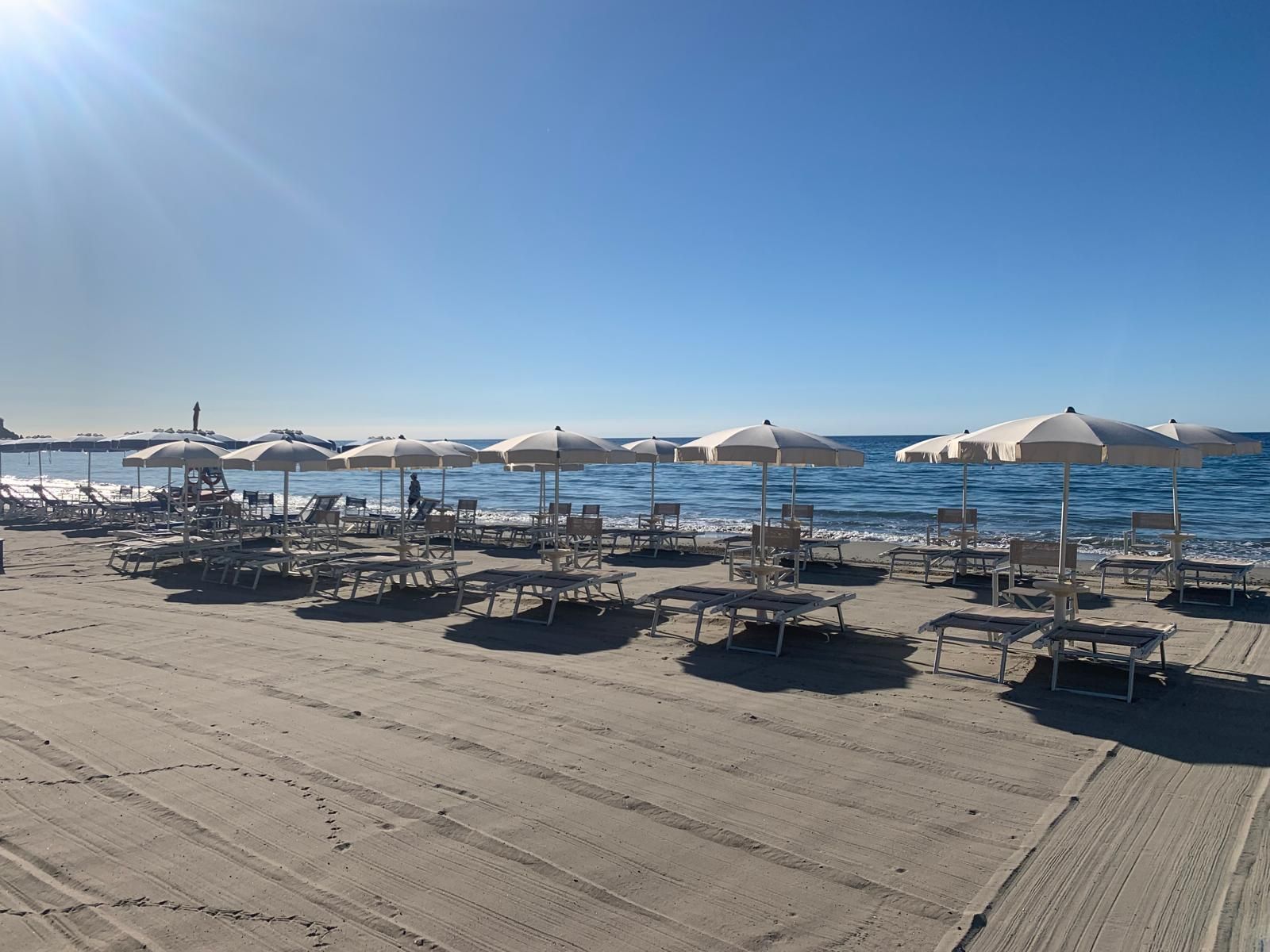 Una spiaggia con molte sedie a sdraio e ombrelloni