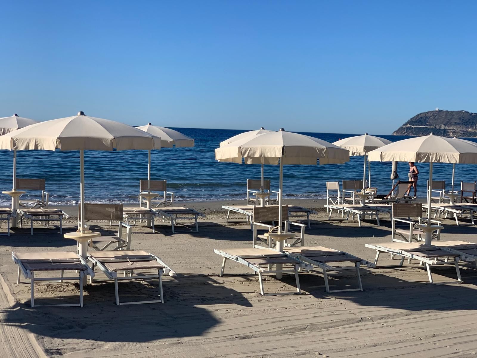 Una spiaggia con molte sedie a sdraio e ombrelloni