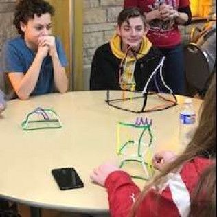 People at a table looking at colorful geometric sculptures.
