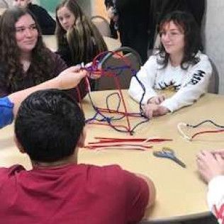 Group of people around a table, crafting with pipe cleaners.