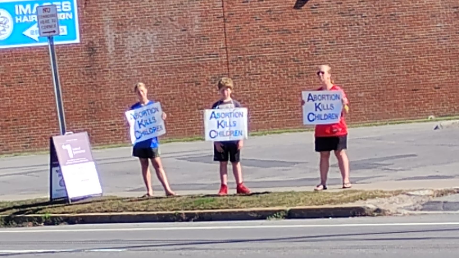 Three people holding signs that read 