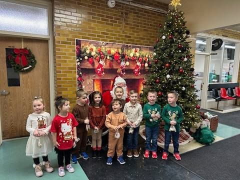 Children with Santa in front of a Christmas tree and fireplace backdrop.