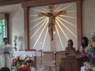 Church service with crucifix, priest, altar, and attendees.