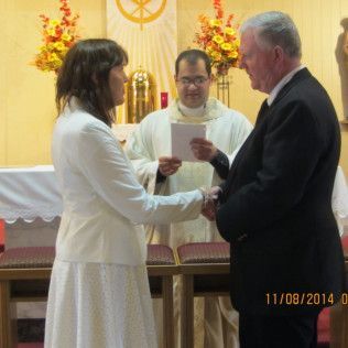 Couple exchanging rings during a wedding ceremony in a church. Priest officiates.
