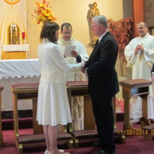 Couple exchanging vows during a church wedding ceremony; priest officiating.