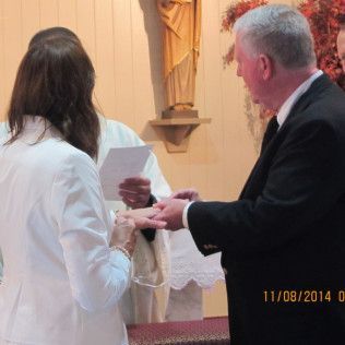 Couple exchanging rings at a wedding ceremony in a church. A priest is officiating.