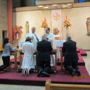 People kneeling at an altar during a religious ceremony in a church.
