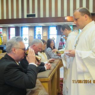 People taking communion in a church. A priest offers the Eucharist.