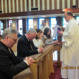 People praying at a church altar; a priest leads the service.