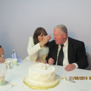 Woman feeding cake to a man at a table, cake in foreground. 