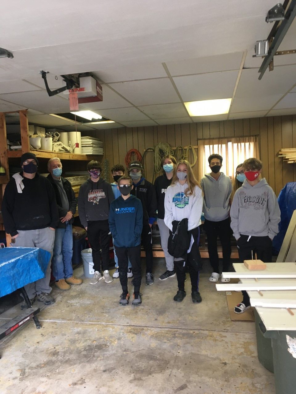 Group of students wearing masks stand in a workshop.