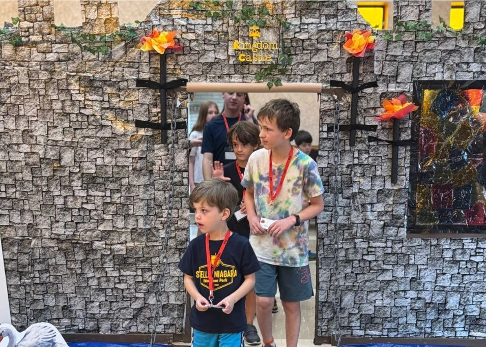 Children entering a doorway decorated as a castle, with flame-like lights.