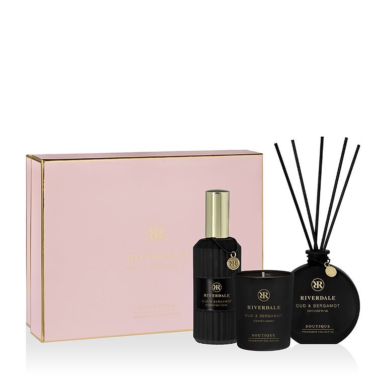 Roze geschenkdoos met drie zwarte geurstokjes en flesjes parfum op een witte achtergrond.