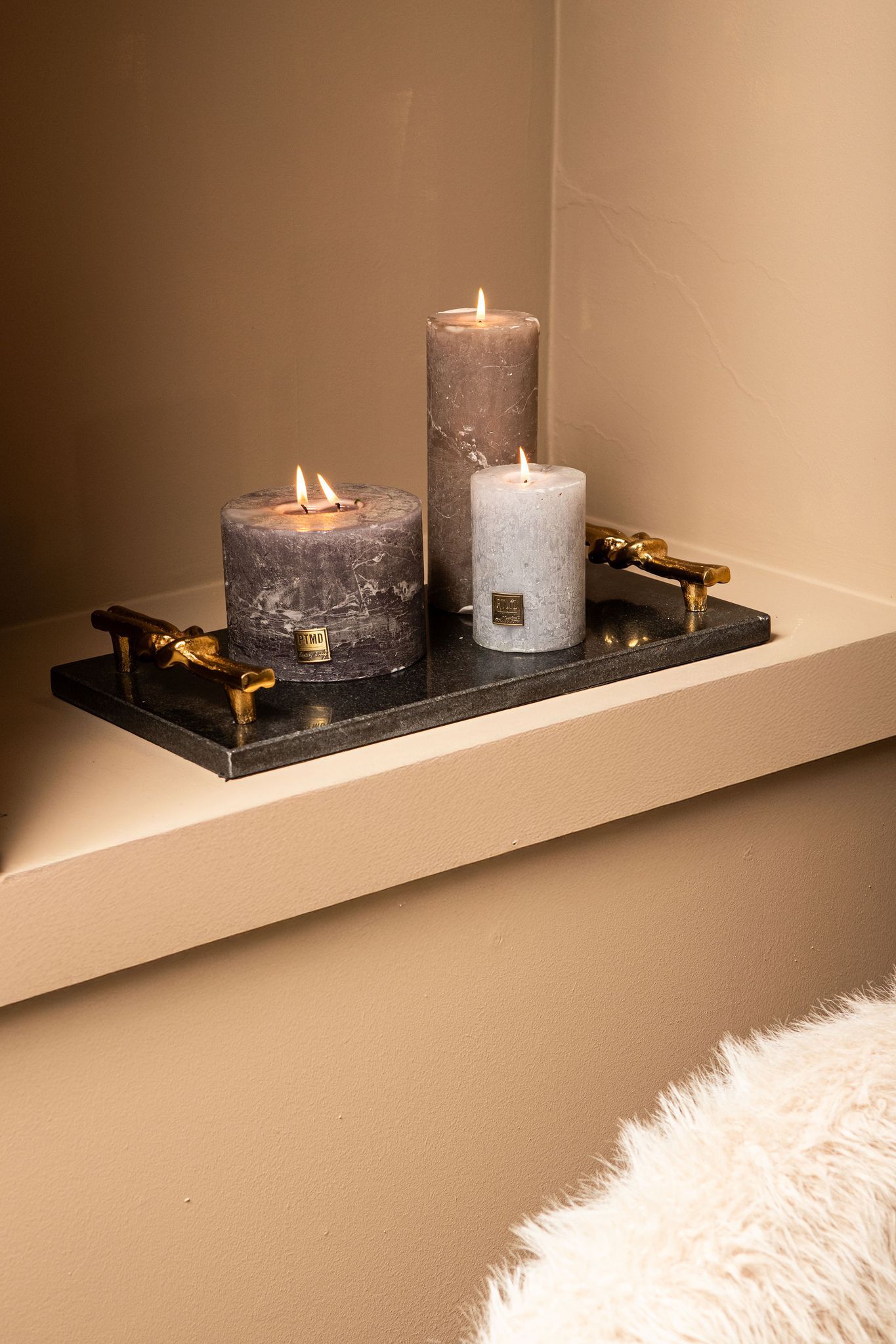 Beige bank met zwarte salontafel, decoratieve wanddecoratie en een raam met zwarte kozijnen.