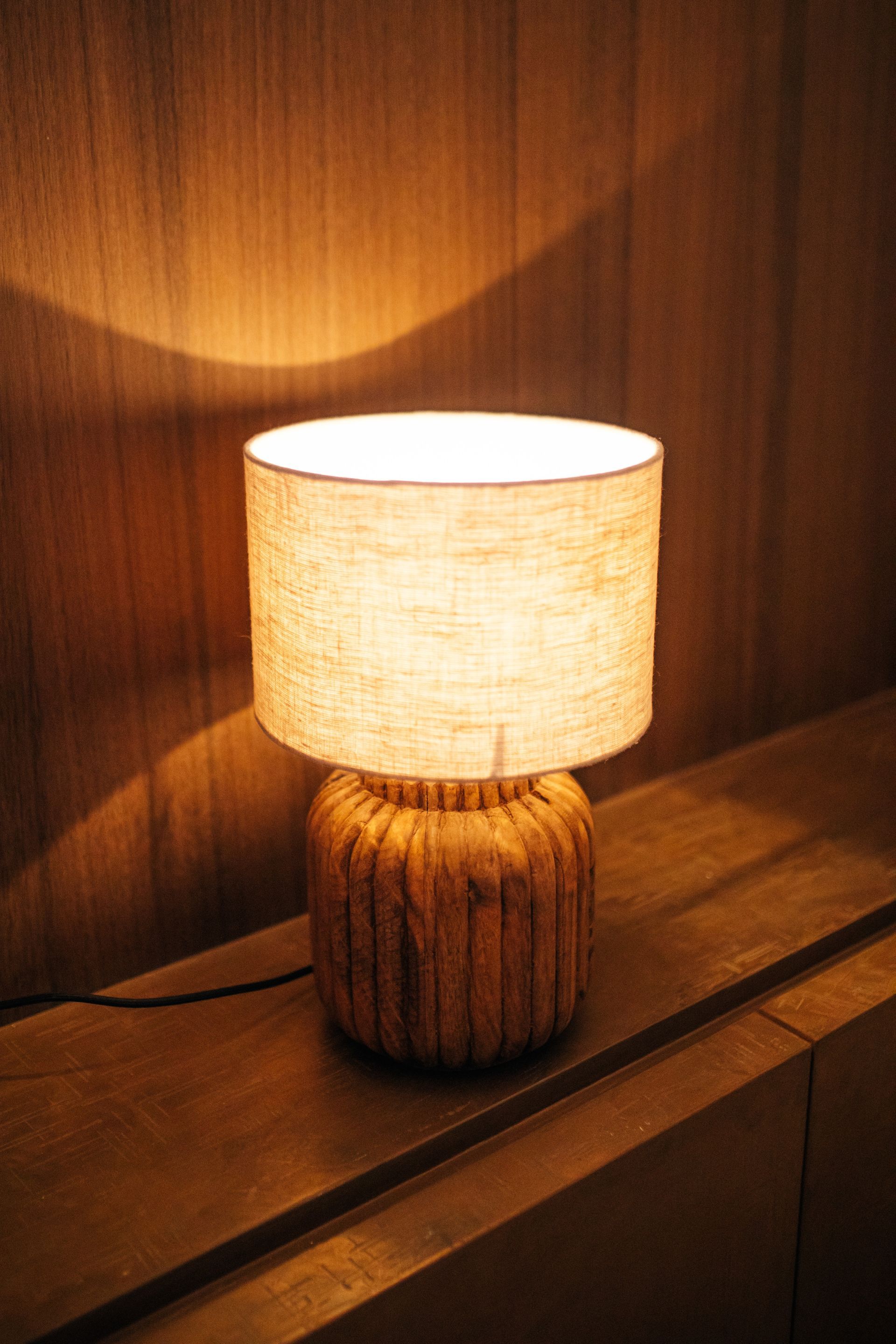 Tafellamp met een beige kap en een voet van gestructureerd hout, inclusief snoer.