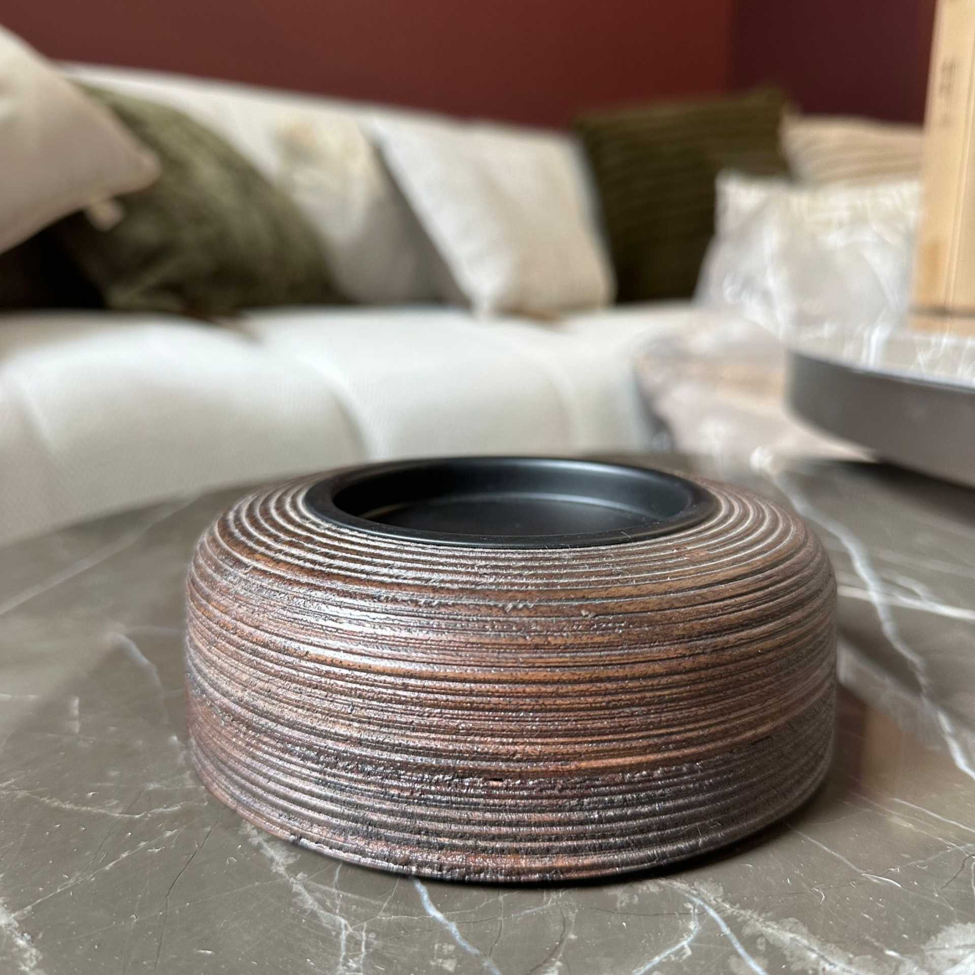Klein, rond, gevlochten mandje op een marmeren tafel in de woonkamer, met een bank op de achtergrond.